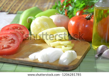 Chopped tomatoes on a board, onions, garlic, greens. Ingredients for cooking salad or soup. Healthy food diet. Photo on top of fresh vegetables, cutting board, oil, knife,