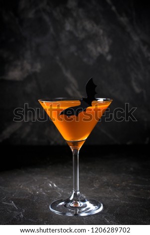 Orange pumpkin  martini Halloween drink for party over black background with copy space