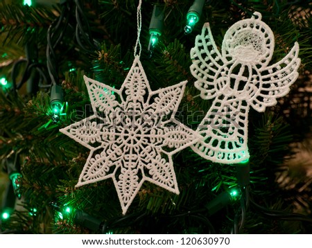 Free-standing lace Christmas star and Christmas angel ornaments on tree with green lights