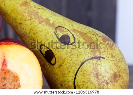 sad drawing on a pear lying near cut fruits and vegetables