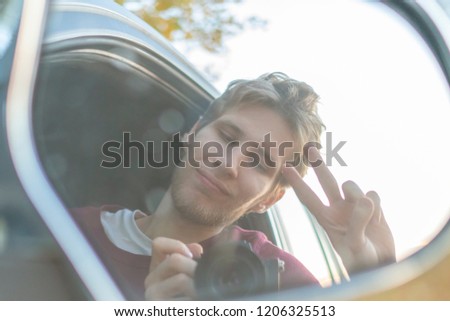 young driver taking a self portrait with professional camera in the car window 