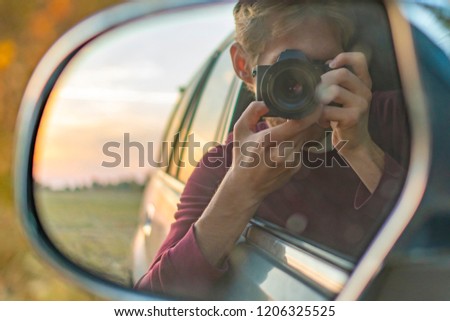 young driver taking a self portrait with professional camera in the car window 