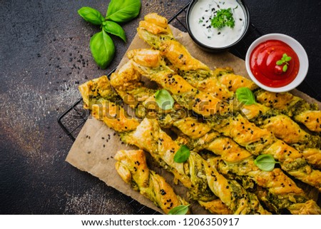Homemade bread sticks with cheese, pesto sauce and black sesame seeds on gray stone vintage background.  Top view.