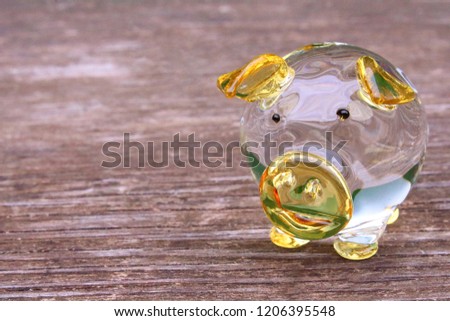 Glass transparent yellow pig on a wooden board. Close-up. Background. Texture.