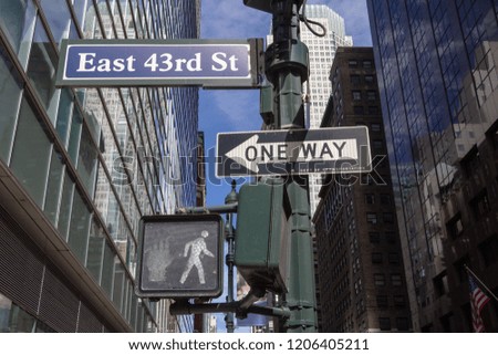 One Way road sign, pedestrian traffic lights with white light on East 43rd Street in New York City
