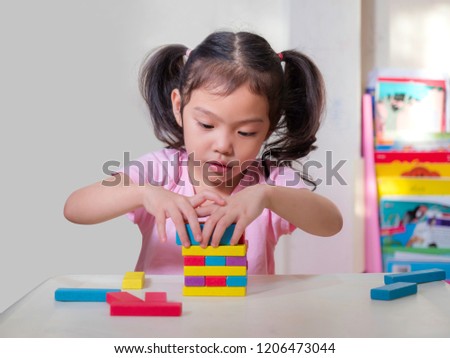 Little cute girl playing wooden blocks at home. Learning of kid.