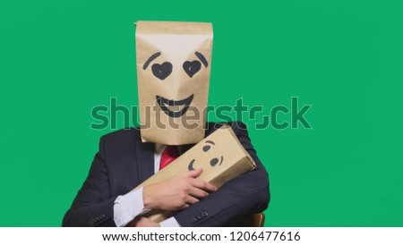 concept of emotions, gestures. a man with a package on his head, with a painted emoticon, smile, enamored eyes. plays with the child painted on the box.