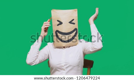 concept of emotions, gestures. a man with paper bags on his head, with a painted emoticon, smile, joy. talking on a cell phone
