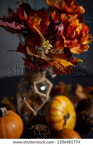 A dark fall table with autumn decorations. flowers, pumpkins and candles 