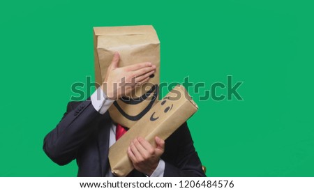 concept of emotions, gestures. man with a package on his head, with a painted emoticon, smile, joy, laughter. plays with the child painted on the box.
