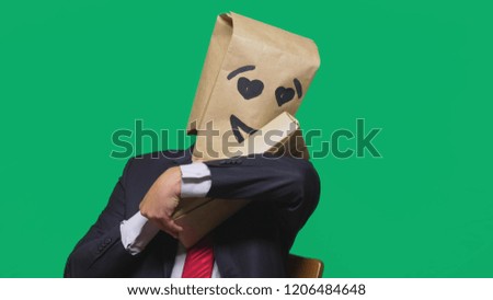 concept of emotions, gestures. a man with a package on his head, with a painted emoticon, smile, enamored eyes. plays with the child painted on the box.