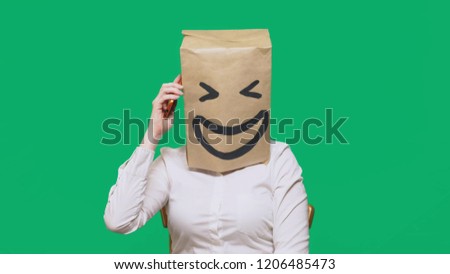 concept of emotions, gestures. a man with paper bags on his head, with a painted emoticon, smile, joy. talking on a cell phone