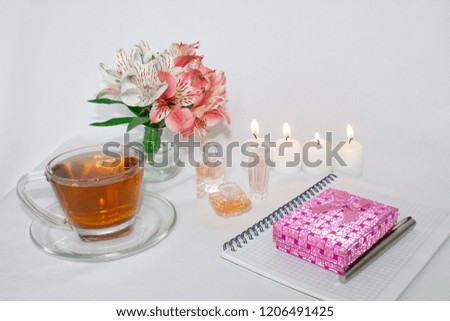 Dressing table with women's accessories. Image of a pink gift box with a bouquet of Alstroemeria flowers, candles, perfume, tea cups, and notepad. With an inscription in a notebook - "For you"