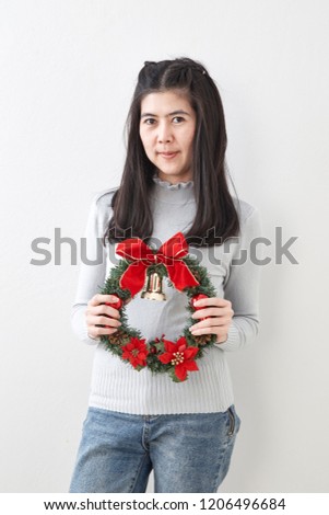 Portrait of beauty young woman with christmas wreath and gift on white wall  background