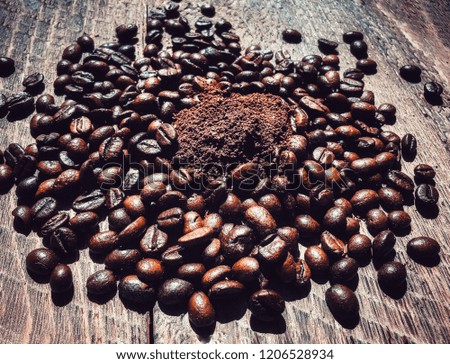 Grounded coffee in centre of Coffee beans on wooden background