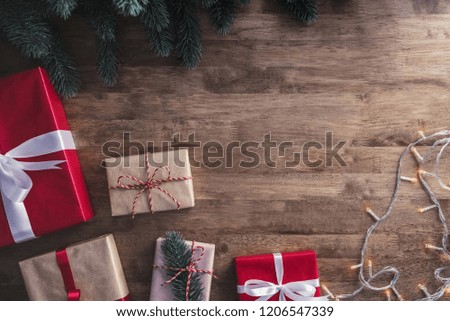 Christmas and new year background with gift boxes, string light and green pine decorations on wood table background top view with copy space