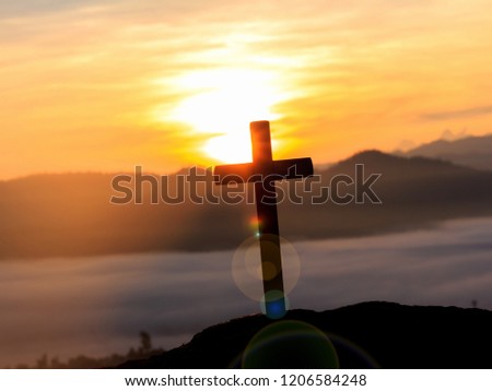 silhouette cross on mountain at mountain sunrise with foggy