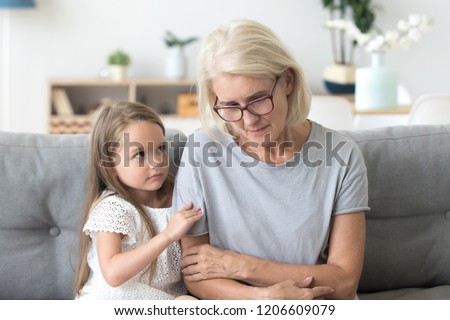 Cute little girl hug upset grandmother feel sad and down comforting her, small granddaughter embrace grandma caressing showing empathy and love, grandchild make peace with granny asking forgiveness Royalty-Free Stock Photo #1206609079