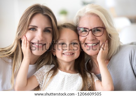 Portrait of three generations of women look at camera posing for family picture, cute little girl hug mom and granny enjoy time at home, smiling mother, daughter and grandmother spend weekend together Royalty-Free Stock Photo #1206609505