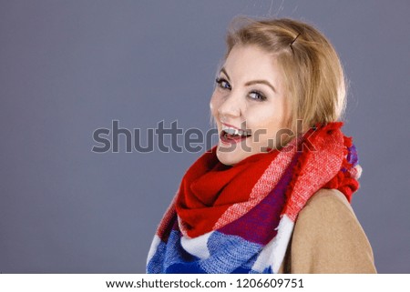 Woman wearing light brown coat and colorful checked scarf. Winter fashion concept.