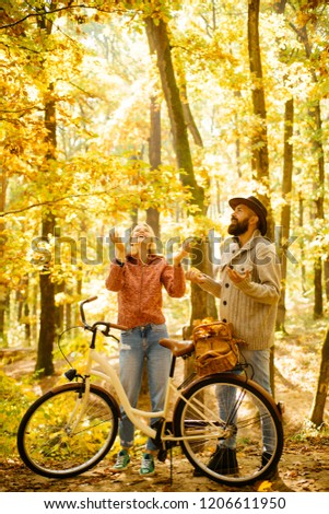 Autumn couple is riding the bicycle in the park. Active people. Outdoors. Autumn woman an bearded man with retro bike in autumnal park. Couple with vintage bike