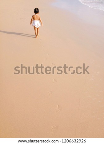 Little girl walking alone at the beach.