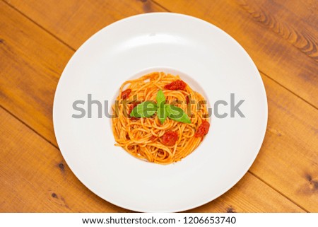 Plate of delicious Italian spaghetti pasta with fresh basil leaves,  with meat, tomato sauce, vegetables and grated parmesan cheese