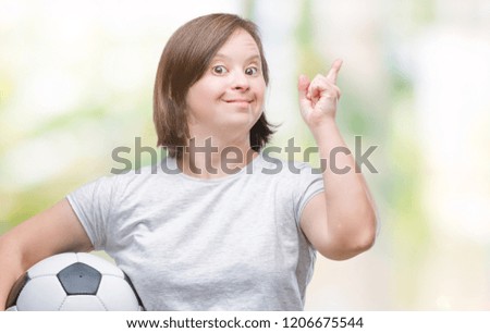 Young adult woman with down syndrome holding soccer football ball over isolated background very happy pointing with hand and finger to the side