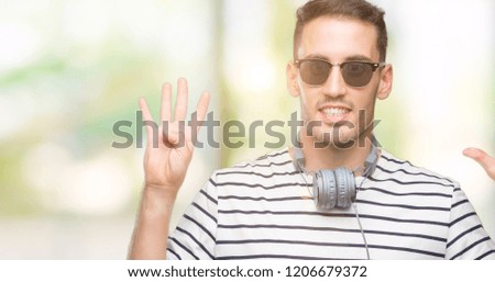 Handsome young man wearing headphones showing and pointing up with fingers number nine while smiling confident and happy.