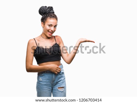 Young braided hair african american with pigmentation blemish birth mark over isolated background smiling cheerful presenting and pointing with palm of hand looking at the camera.