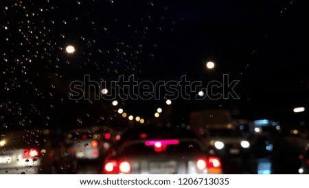 Colorful bokeh with street light at night. Raindrops on car windshield, traffic in the city on a rainy day. Blur and dark background. Selective focus.