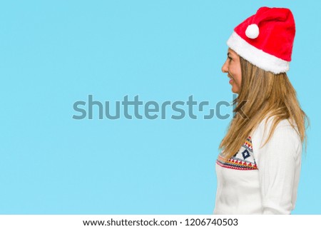 Middle age adult woman wearing winter sweater and chrismat hat over isolated background looking to side, relax profile pose with natural face with confident smile.