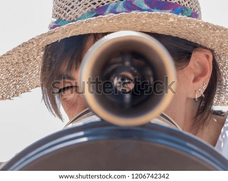 Woman using a binoculars in the city looking to you