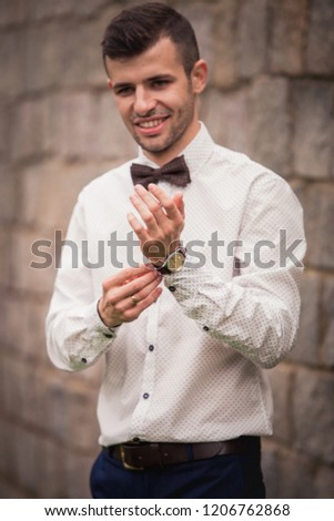 stylish bride's husband, with dark hair and unshaven face, in a shirt, preparing for a wedding