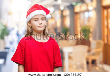 Young beautiful girl wearing christmas hat over isolated background with serious expression on face. Simple and natural looking at the camera.