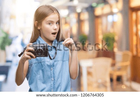 Young beautiful girl taking photos using vintage camera over isolated background surprised with an idea or question pointing finger with happy face, number one