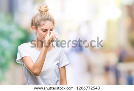Young beautiful blonde woman wearing white t-shirt over isolated background tired rubbing nose and eyes feeling fatigue and headache. Stress and frustration concept.