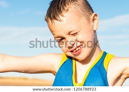A handsome little boy with ADHD, Autism, Asperger Syndrome happy, smiling, being energetic and having fun posing for pictures by the sea