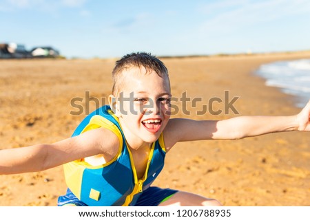 A handsome little boy with ADHD, Autism, Asperger Syndrome happy, smiling, being energetic and having fun posing for pictures by the sea