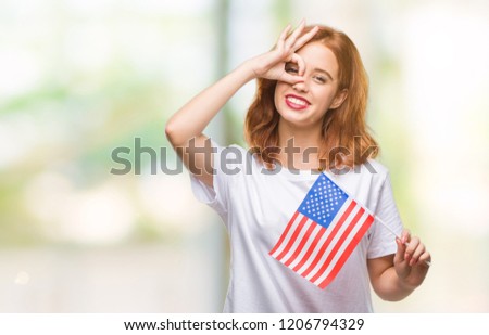Young beautiful woman holding flag of america over isolated background with happy face smiling doing ok sign with hand on eye looking through fingers