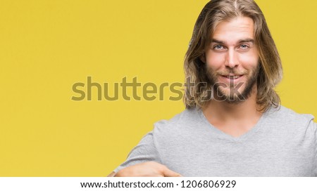 Young handsome man with long hair over isolated background holding football ball with surprise face pointing finger to himself
