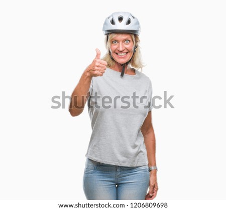 Middle age caucasian cyclist woman wearing safety helmet over isolated background doing happy thumbs up gesture with hand. Approving expression looking at the camera with showing success.