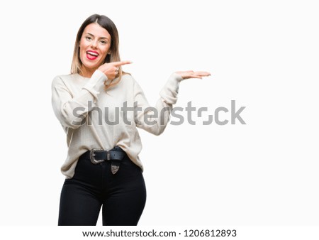 Young beautiful woman casual white sweater over isolated background amazed and smiling to the camera while presenting with hand and pointing with finger.