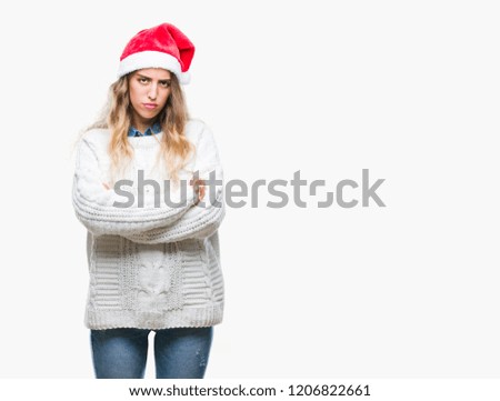 Beautiful young blonde woman wearing christmas hat over isolated background skeptic and nervous, disapproving expression on face with crossed arms. Negative person.