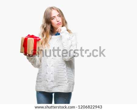 Beautiful young blonde woman holding gift over isolated background serious face thinking about question, very confused idea