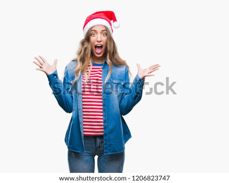 Beautiful young blonde woman wearing christmas hat over isolated background celebrating crazy and amazed for success with arms raised and open eyes screaming excited. Winner concept