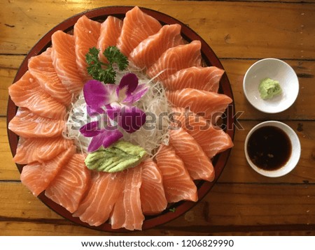 salmon sashimi put into white bowl on wood plate.