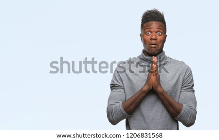 Young african american man over isolated background begging and praying with hands together with hope expression on face very emotional and worried. Asking for forgiveness. Religion concept.