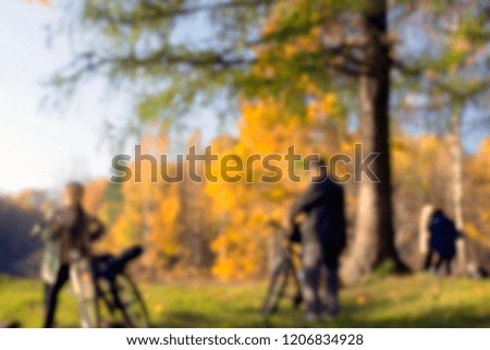 Unfocused blurred bright autumn photo in the park. People with bicycles, contrast defocused photo. Bikes in the park in autumn mood. Golden hour, sunset