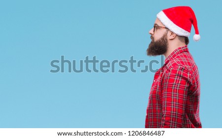 Young caucasian man wearing christmas hat over isolated background looking to side, relax profile pose with natural face with confident smile.